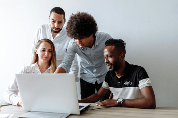 Diverse marketing team collaborating on a health campaign strategy around a laptop in an office setting.